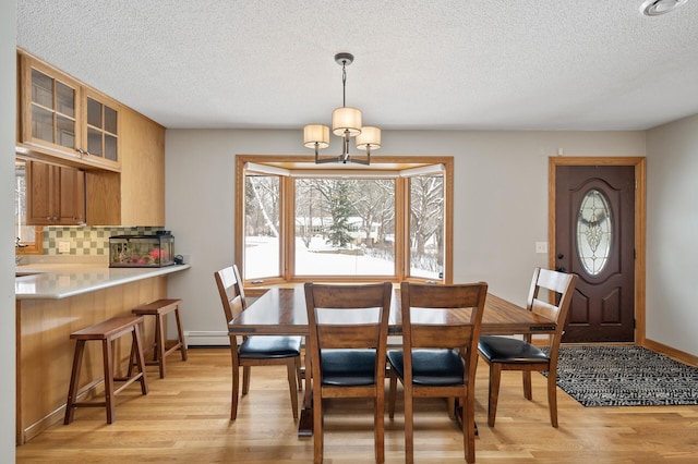 dining room featuring a baseboard heating unit, a textured ceiling, and light wood-type flooring