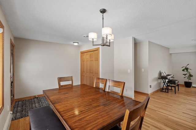 dining area with a baseboard radiator, an inviting chandelier, a textured ceiling, and light wood-type flooring