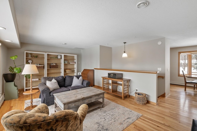 living room with baseboard heating, light hardwood / wood-style flooring, and a textured ceiling