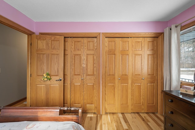 bedroom featuring two closets and light hardwood / wood-style floors