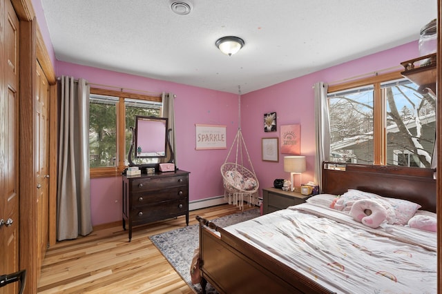 bedroom with multiple windows, light hardwood / wood-style flooring, and a textured ceiling