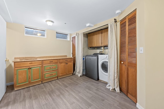 clothes washing area featuring cabinets, washer and dryer, and light wood-type flooring