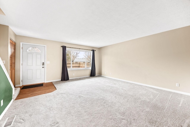 foyer entrance featuring a textured ceiling and carpet