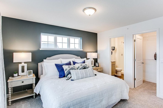 bedroom featuring carpet flooring, connected bathroom, and a walk in closet