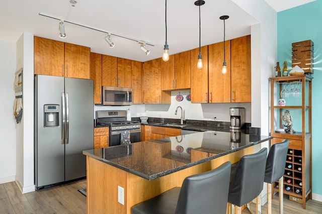 kitchen with a kitchen breakfast bar, stainless steel appliances, hanging light fixtures, and sink