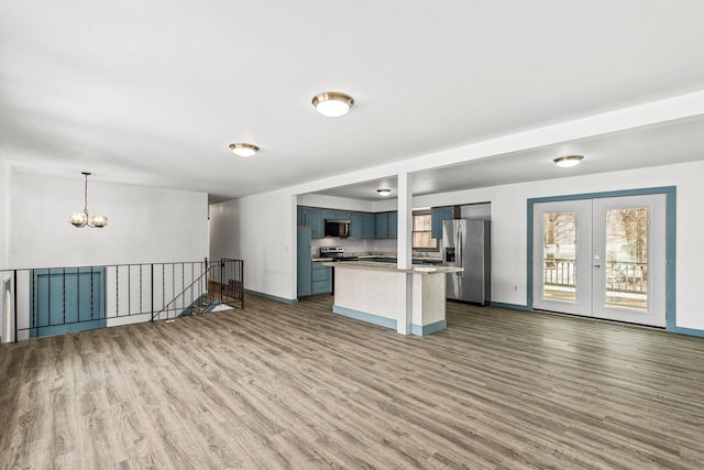 kitchen featuring dark wood-type flooring, blue cabinets, decorative light fixtures, appliances with stainless steel finishes, and a notable chandelier