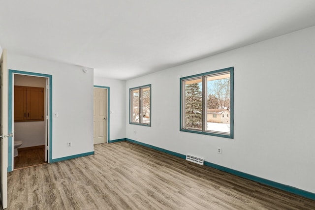 unfurnished bedroom featuring ensuite bath, light hardwood / wood-style flooring, and a closet