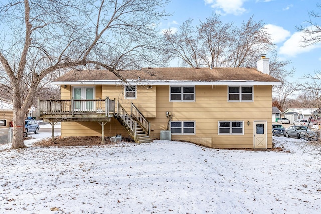 snow covered back of property featuring a wooden deck, cooling unit, and french doors