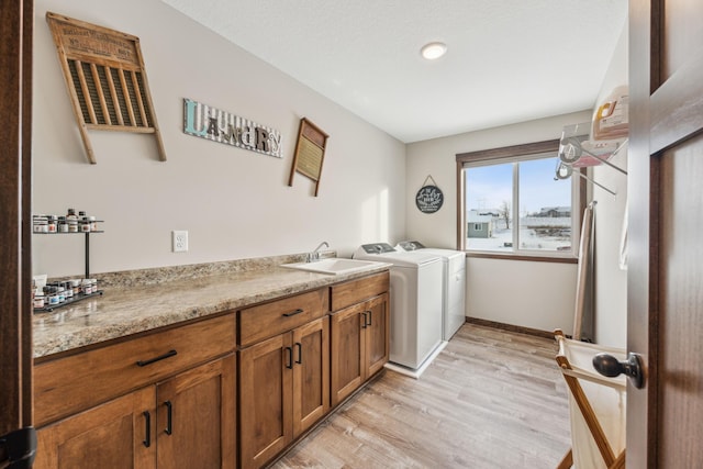 laundry room featuring washing machine and dryer, cabinets, light hardwood / wood-style floors, and sink