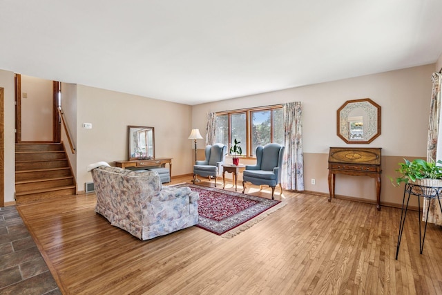 living area with stairway, wood finished floors, and baseboards