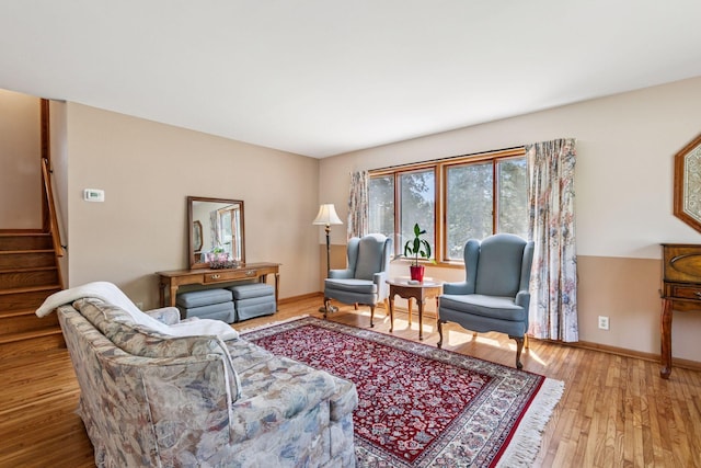 living area featuring wood finished floors, stairway, and baseboards