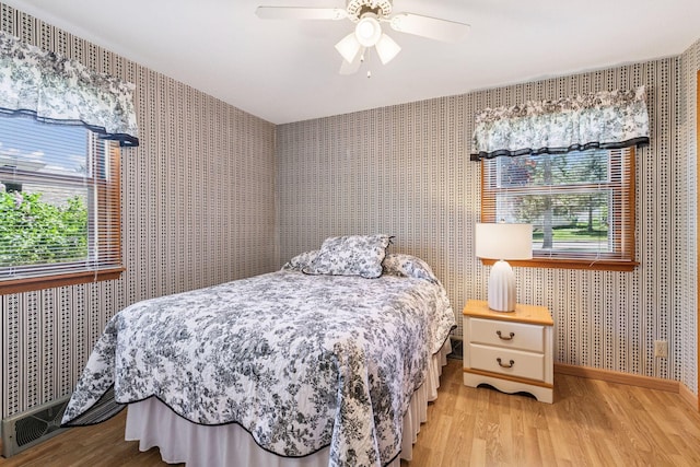 bedroom featuring wallpapered walls, light wood finished floors, baseboards, and ceiling fan