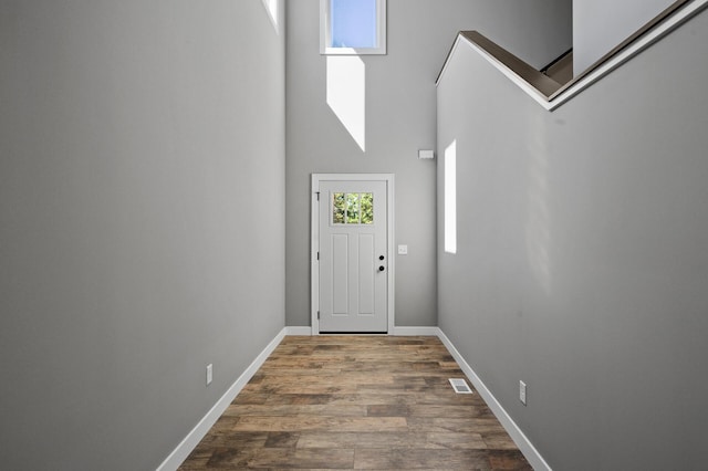 entrance foyer with visible vents, a high ceiling, baseboards, and wood finished floors