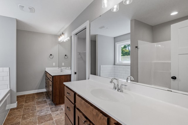 full bath featuring two vanities, a sink, baseboards, a bath, and a walk in closet