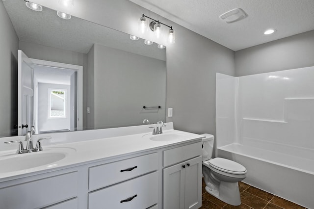 bathroom featuring a textured ceiling, toilet, a sink, visible vents, and double vanity