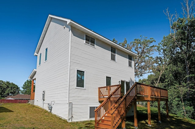 rear view of property featuring stairs, a lawn, and a wooden deck