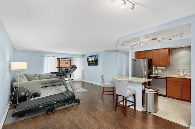 workout area with a textured ceiling, light wood-type flooring, and sink