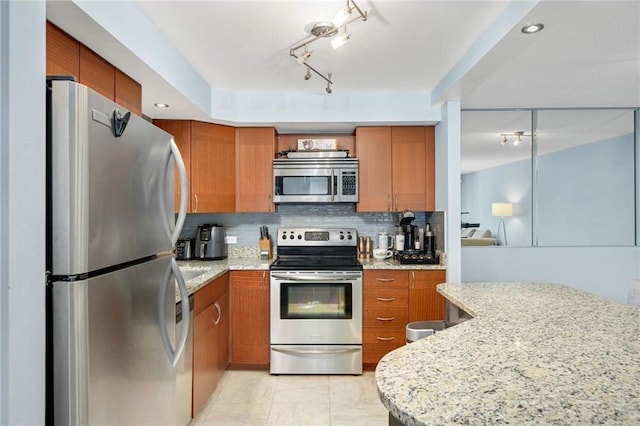 kitchen with appliances with stainless steel finishes, tasteful backsplash, and light stone counters