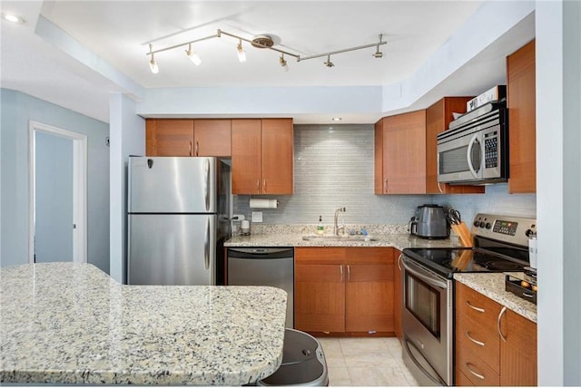 kitchen featuring light stone countertops, decorative backsplash, stainless steel appliances, sink, and light tile patterned floors