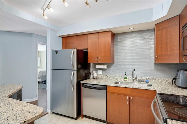 kitchen featuring sink, stainless steel appliances, tasteful backsplash, light stone counters, and light tile patterned floors