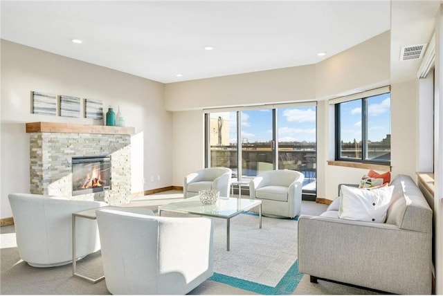 living room with light carpet, a stone fireplace, and a wealth of natural light