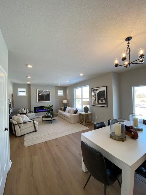 dining space with light wood-type flooring, a textured ceiling, and a notable chandelier