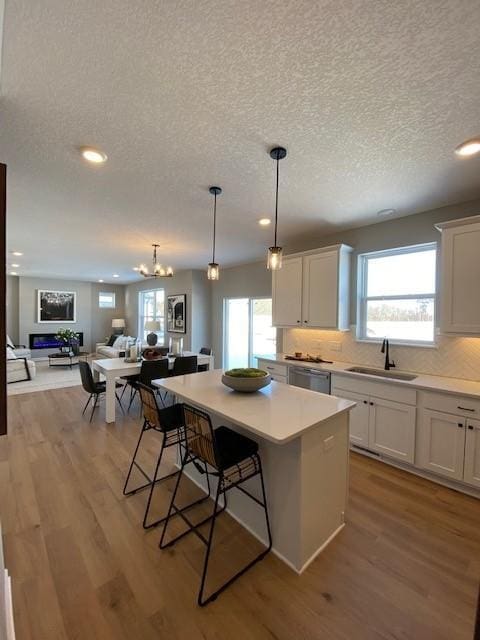 kitchen with a kitchen breakfast bar, sink, a center island, light hardwood / wood-style floors, and white cabinetry