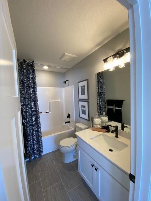 full bathroom with shower / bath combination with curtain, vanity, and toilet