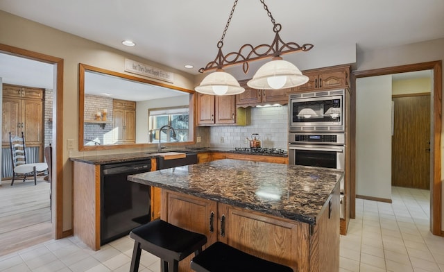 kitchen featuring sink, stainless steel appliances, a center island, decorative backsplash, and decorative light fixtures