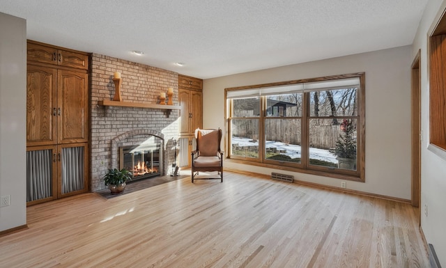 sitting room with a fireplace, a textured ceiling, and light wood-type flooring