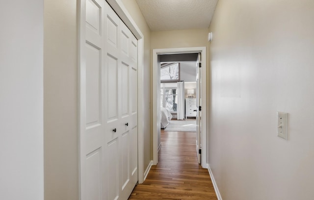 corridor with dark hardwood / wood-style floors and a textured ceiling