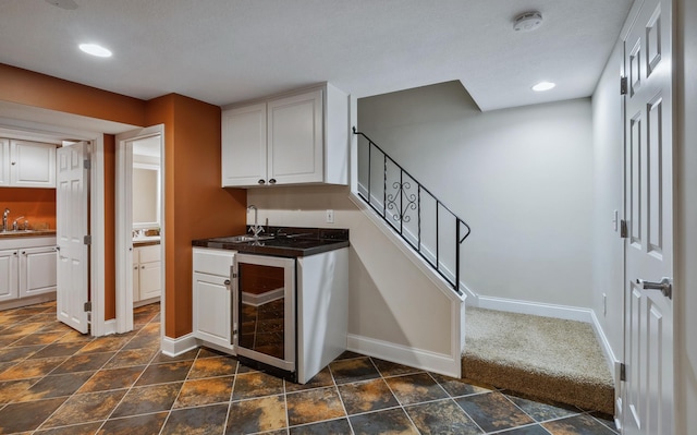 kitchen featuring white cabinetry, sink, wine cooler, and dark carpet