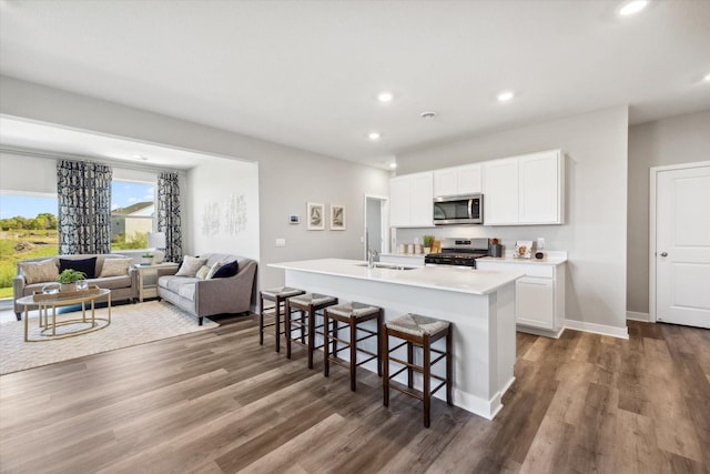 kitchen with a breakfast bar, a kitchen island with sink, sink, white cabinetry, and stainless steel appliances