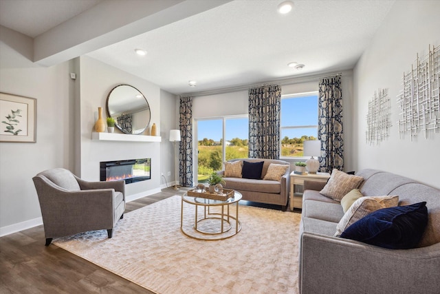 living room featuring a glass covered fireplace, wood finished floors, recessed lighting, and baseboards