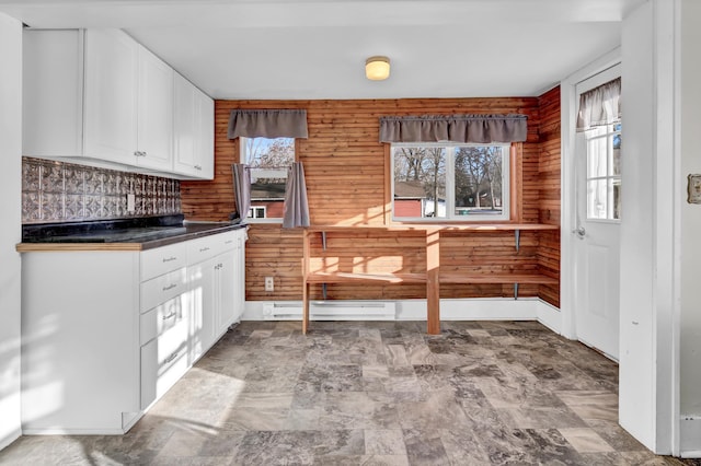 kitchen with tasteful backsplash, white cabinetry, wooden walls, and a baseboard radiator