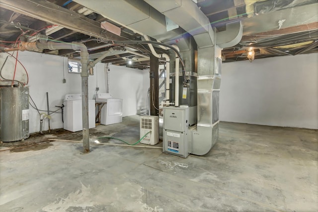 basement featuring heating unit, electric water heater, and independent washer and dryer