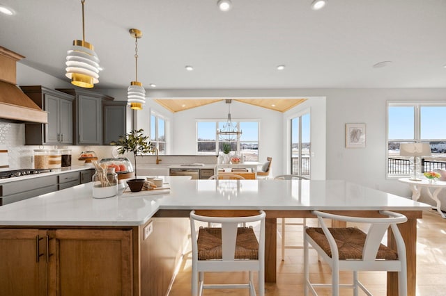 kitchen with appliances with stainless steel finishes, lofted ceiling, hanging light fixtures, and a spacious island