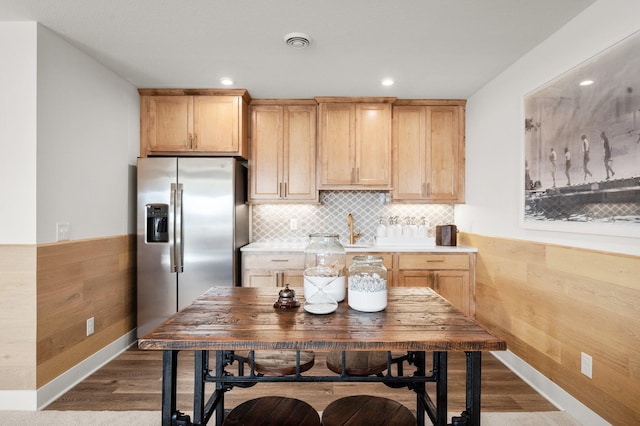 kitchen featuring stainless steel fridge with ice dispenser, light brown cabinets, and backsplash