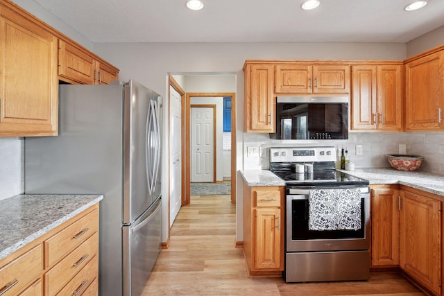 kitchen featuring light stone counters, stainless steel appliances, light hardwood / wood-style floors, and tasteful backsplash