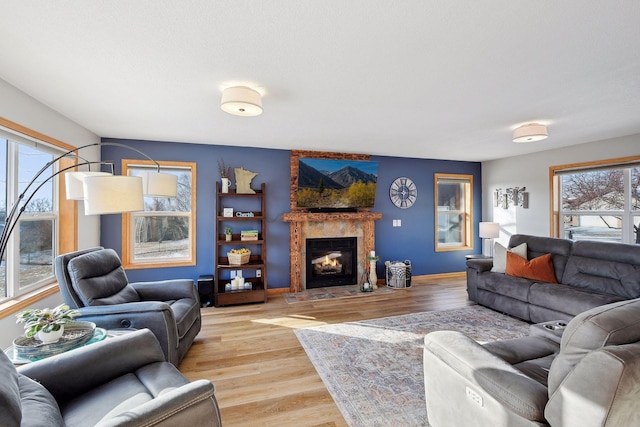 living room featuring a large fireplace, light wood-type flooring, and a wealth of natural light