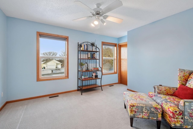 sitting room with ceiling fan, carpet floors, and a textured ceiling