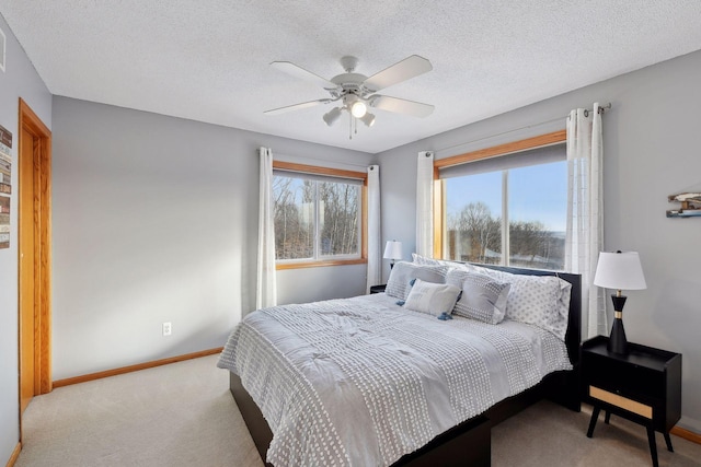 bedroom with ceiling fan, light colored carpet, multiple windows, and a textured ceiling