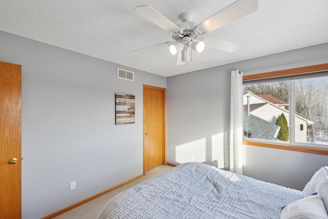 bedroom featuring ceiling fan, light colored carpet, and a textured ceiling