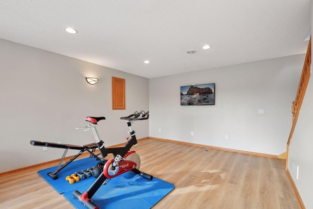 workout area featuring a textured ceiling and light hardwood / wood-style flooring