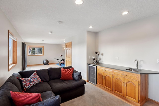 carpeted living room featuring wine cooler, wet bar, and a textured ceiling