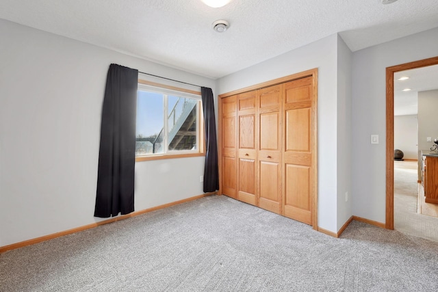 unfurnished bedroom with a closet, light carpet, and a textured ceiling