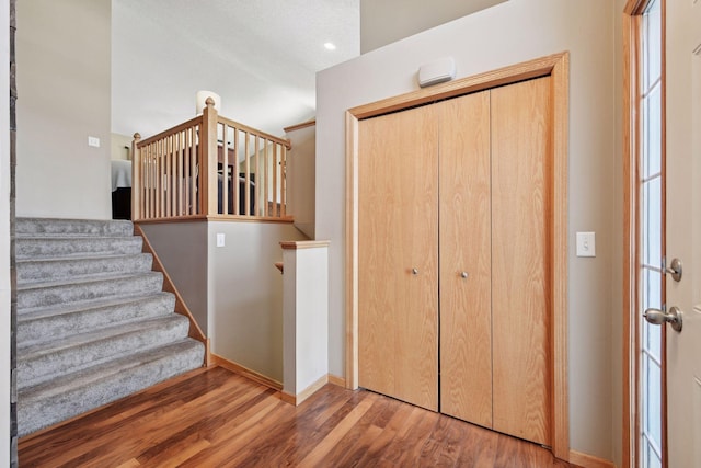 staircase featuring vaulted ceiling, wood finished floors, and baseboards