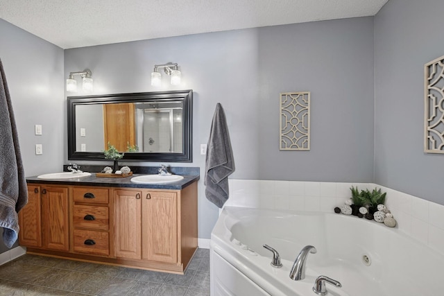 bathroom featuring a sink, a textured ceiling, double vanity, and a whirlpool tub