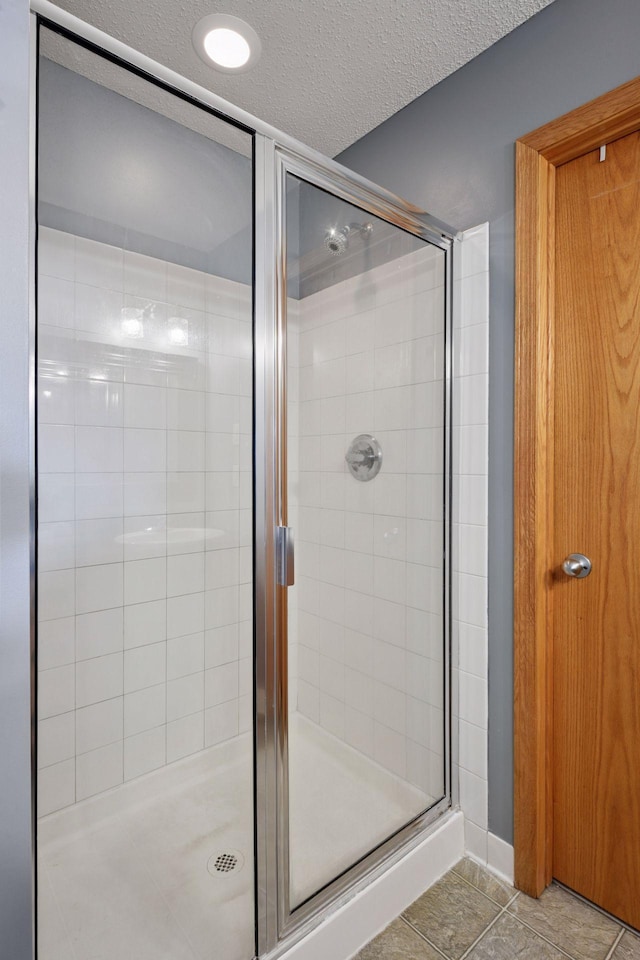 full bath with tile patterned floors, a shower stall, and a textured ceiling