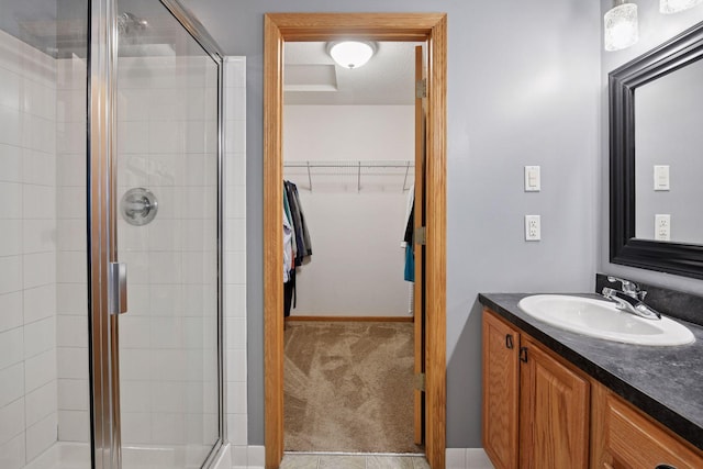 bathroom with a shower stall, vanity, and a walk in closet